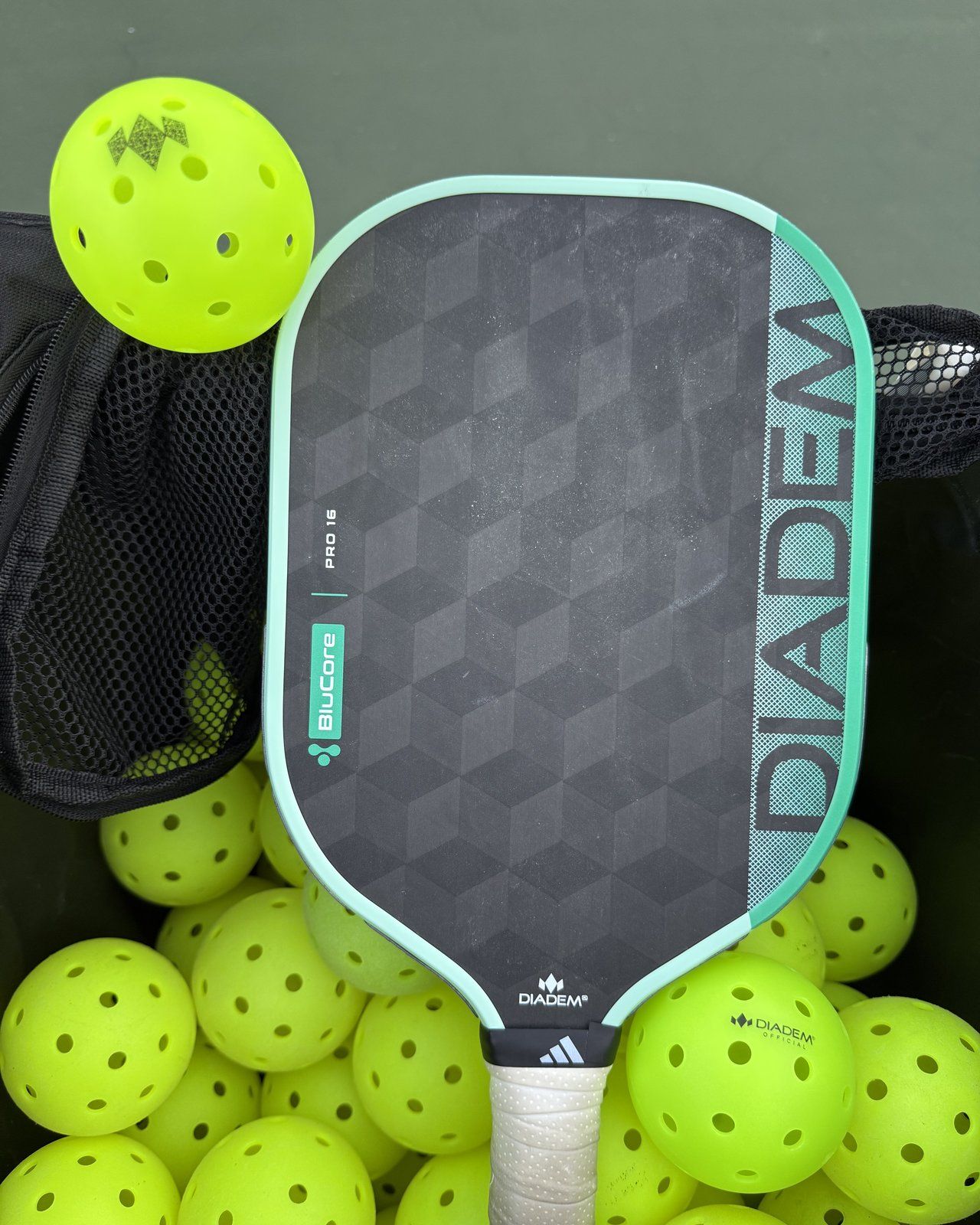 A Diadem BluCore Pro 16 paddle resting on Diadem pickleballs.